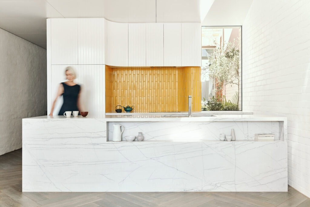 Modern kitchen featuring a sleek marble island, minimalist cabinetry, and large window with natural.