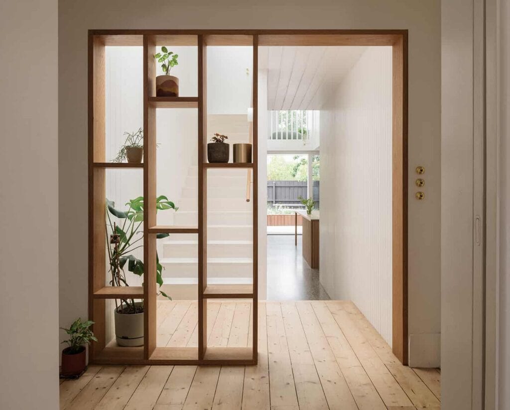 Modern wooden room divider with built-in shelves in minimalist interior design.