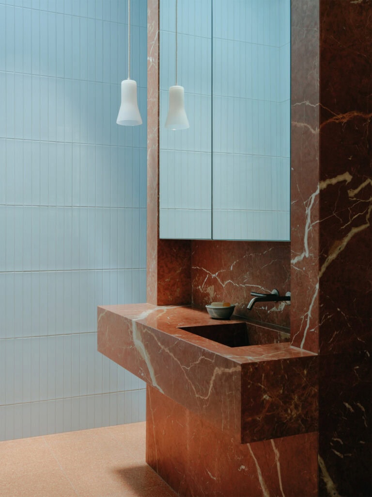 Modern bathroom with blue tiles and a marble sink and wall.